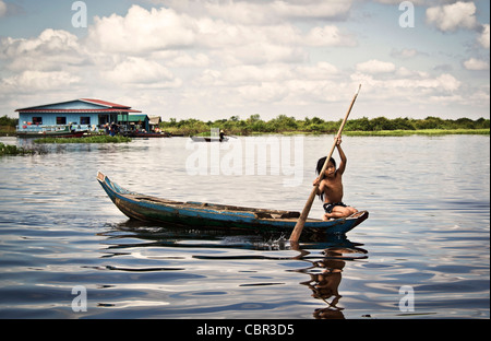 A young girl paddles a small boat through the water on the river sangker, between siem reap and battambang, in cambodia Stock Photo