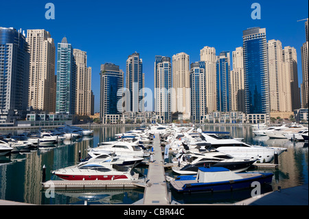 Boats in harbour at Yacht Club Marina with apartment towers to rear in New Dubai in United Arab Emirates Stock Photo