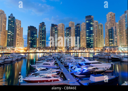 Boats in harbour in the evening at Yacht Club Marina with apartment towers to rear in New Dubai in United Arab Emirates Stock Photo