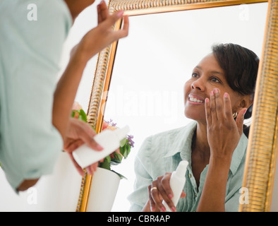 Black woman applying moisturizer Stock Photo