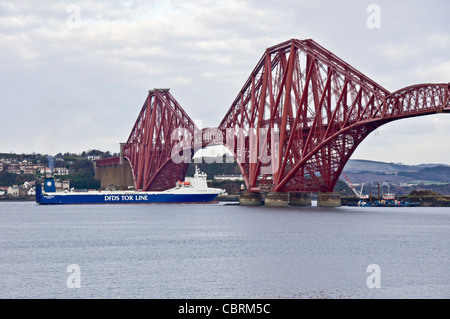 Newly painted Forth Rail Bridge seen from South Queensferry in Scotland with DFDS RoRo car ferry Tor Finlandia passing through Stock Photo