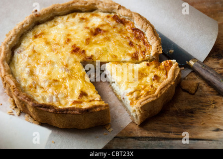 Little Quiche Lorraine on curled greaseproof paper with knife Stock Photo