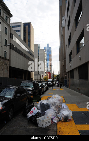 White sky 'urban canyon' portrait plastic bags of rubbish on pavement by parked cars, Tech Place, Downtown Brooklyn, New York Stock Photo