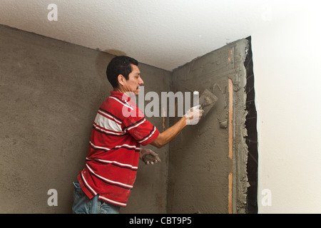 Hispanic man from Mexico working his own construction business in the USA replaces shower spreading cement talking to employee. MR © Myrleen Pearson Stock Photo