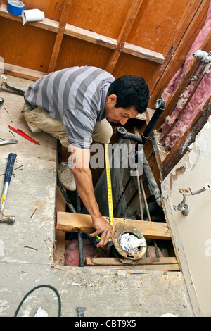 Hispanic man from Mexico working his own construction business in the USA replaces upstairs shower. MR © Myrleen Pearson Stock Photo