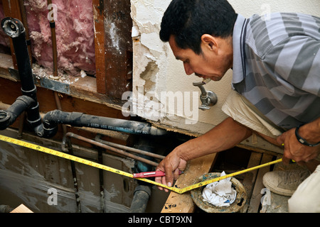 Hispanic man from Mexico working his own construction business in the USA replaces upstairs shower. MR © Myrleen Pearson Stock Photo