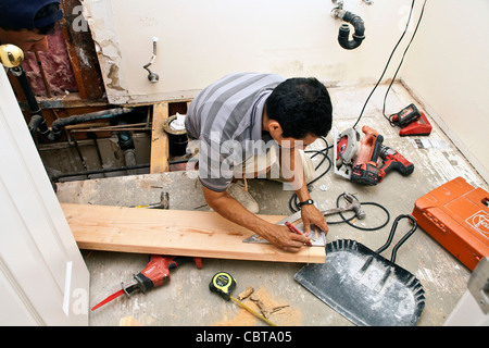 Hispanic man from Mexico working his own construction business in the USA replaces support beam in upstairs bathroom USA. MR © Stock Photo