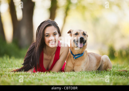 Caucasian woman laying in grass with dog