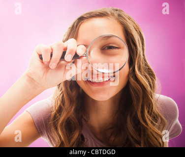 Caucasian teenager peering through magnifying glass Stock Photo