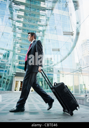 Caucasian businessman pulling suitcase outdoors Stock Photo