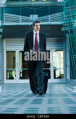 Caucasian businessman pulling suitcase outdoors Stock Photo