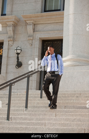 Black businessman talking on cell phone and walking down stairs