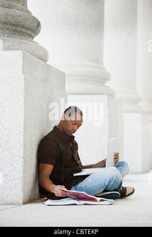 Black college student doing homework outdoors Stock Photo