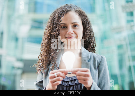 Caucasian businesswoman holding glowing light bulb Stock Photo