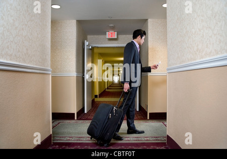 Asian businessman pulling suitcase in hotel Stock Photo