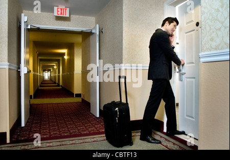 Asian businessman using cell phone and entering hotel room Stock Photo