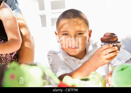 Mixed race boy eating chocolate cupcake Stock Photo