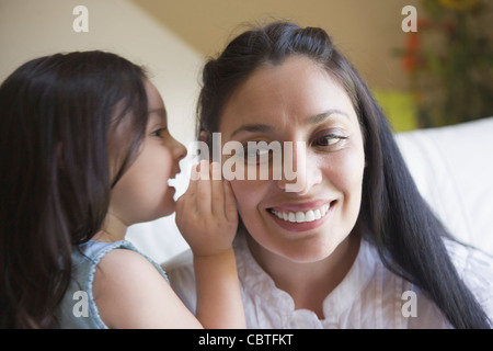 Hispanic girl whispering to mother Stock Photo