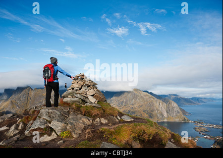 Female hiker enjoys spectacular view over mountains and fjords from Reinebringen, Lofoten islands, Norway Stock Photo