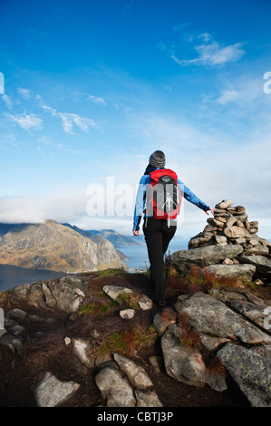 Female hiker enjoys spectacular view over mountains and fjords from Reinebringen, Lofoten islands, Norway Stock Photo