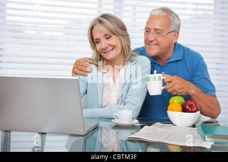 Happy couple using laptop while having breakfast Stock Photo