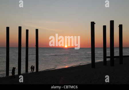 Sunset  through some of the remaining pier supports of the West Pier, on Brighton beach, East Sussex, UK. Stock Photo