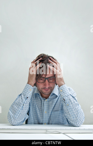 Businessman with headache looking down at the computer keyboard Stock Photo