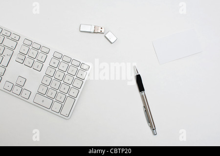 Office desktop, a keyboard, pen and a usb flash drive. Stock Photo