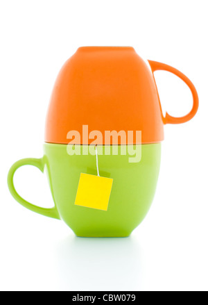 orange and green tea cups with tea bag inside with empty yellow label Stock Photo