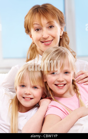 A young family of woman and twin sisters looking at camera Stock Photo