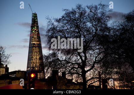 The Shard, under construction at night sits behind the silhouette of a giant tree. The Shard (aka The Shard of Glass) is being built on the south side of the city near London Bridge. Shard London Bridge, previously known as London Bridge Tower, and also known as the Shard of Glass. Stock Photo