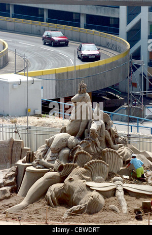 Cars from Brighton Marina drive past the giant sand sculptures exhibition at Black Rock today which were opened to the public Stock Photo