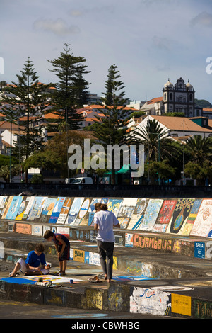 A visiting yachtsman hand-paints a ship's calling card on the marina walls in Horta, Faial island in the Azores Stock Photo