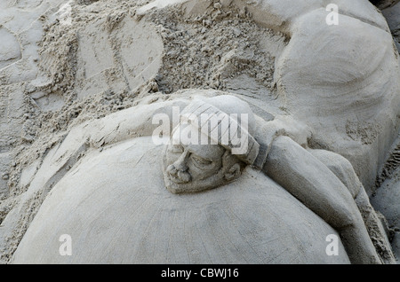 Sand sculpture carving of head  Shore South bank of river Thames London Uk Stock Photo