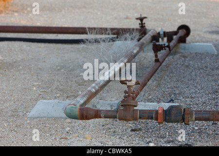 Close up of oil transfer pipes leading to and from and oil well head on an oil well Stock Photo