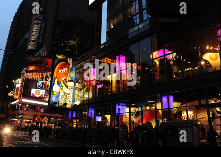 Twilight red purple neon lights glass facade M&M World candy store towards Hershey's, West 48th Street, 7th Avenue, New York Stock Photo