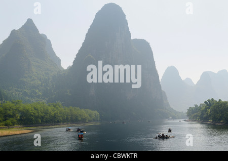 Tour boat rafts on the Li river Guangxi China with sugarcone karst mountain peaks receding in the haze Stock Photo