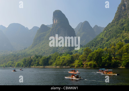 Tour boat rafts on the Li river Guangxi with pointy karst mountain peaks in the haze Peoples Republic of China Stock Photo