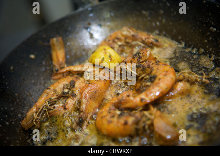 Spanish prawn gambas cooking in a frying pan, with lemon Stock Photo