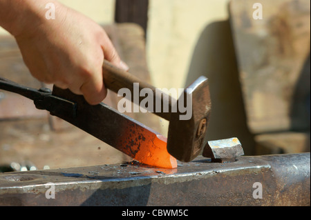 Hammering glowing steel - to strike while the iron is hot. Stock Photo