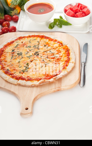 Italian original thin crust pizza Margherita with gazpacho soup and watermelon on side,and vegetables on background Stock Photo