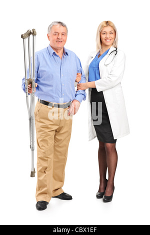 Full length portrait of a female doctor or nurse holding a senior patient with crutches Stock Photo