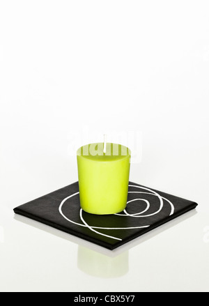 One green candle on square coaster Stock Photo