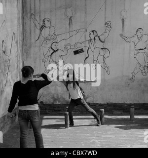 Pingyao, Shanxi, China. Young female posing in front of a martial arts mural. Stock Photo