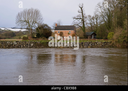 Idyllic Nethouse Cottage on the banks of the River Wye in flood near Hay-on-Wye Powys Wales UK Stock Photo