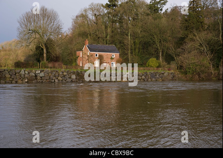 Idyllic Nethouse Cottage on the banks of the River Wye in flood near Hay-on-Wye Powys Wales UK Stock Photo