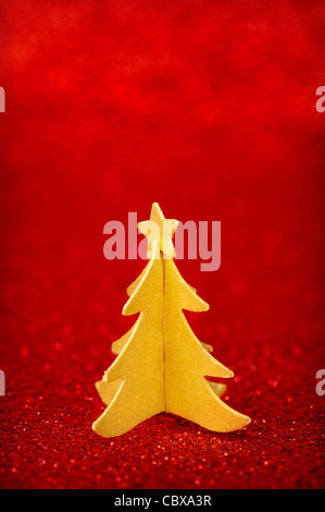 Golden paper Christmas tree with star on top, over red glitter background Stock Photo