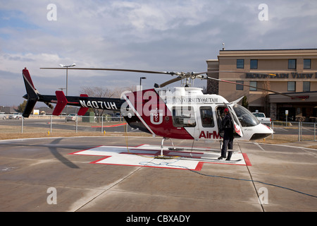 Helicopter AirMed from University of Utah Medical Center ready for emergency flight in front of a small hospital with pilot. Stock Photo