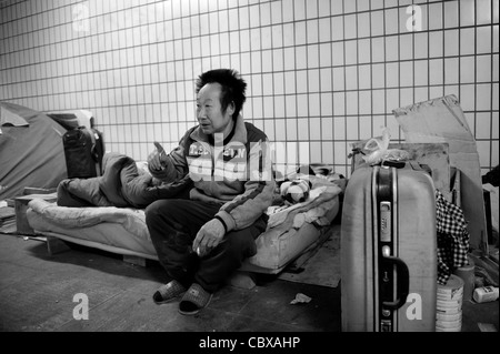 Beijing. Mr. Wang ShiQuan, a homeless person, sitting on his mattress in an underground pedestrian tunnel. Stock Photo