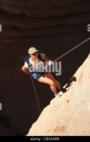 canyoneering asian woman rappels into a shadowed canyon in the Grand ...